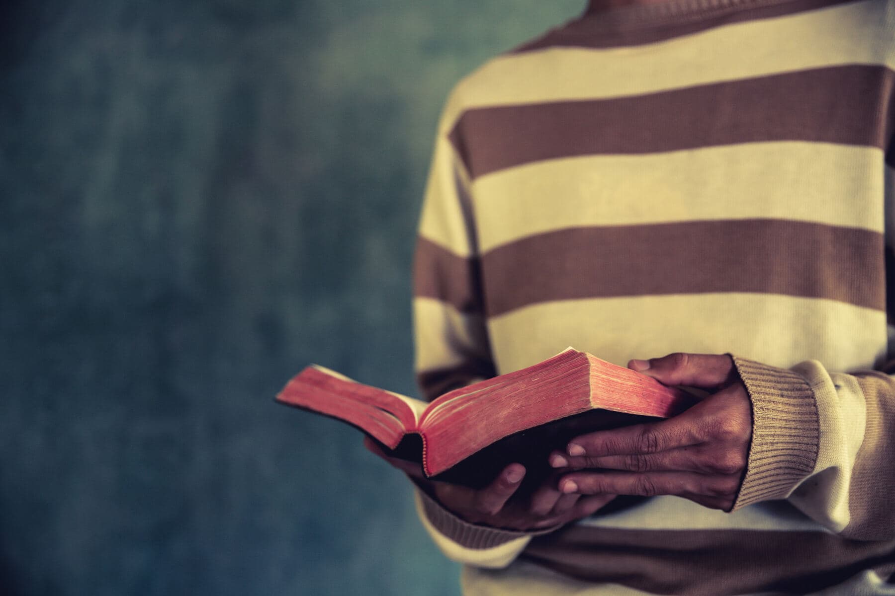 A person holding an open Bible in low light